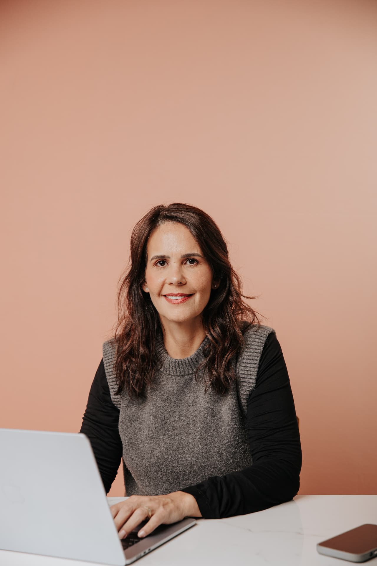 Veridiana Tossato trabalhando no laptop, sorrindo